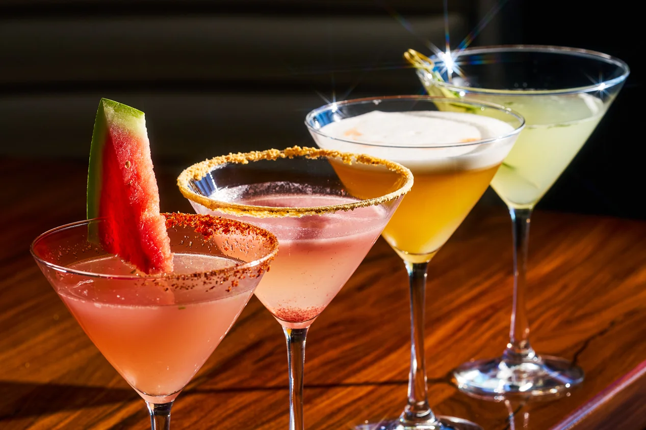 A trio of signature STK cocktails styled on the bar, garnished with citrus, watermelon, and a cinnamon rim
