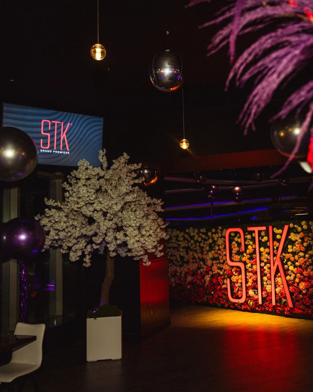 STK Niagara Falls corporate event setup with the STK floral wall, branded screen, cherry blossom tree, and chrome balloon installation