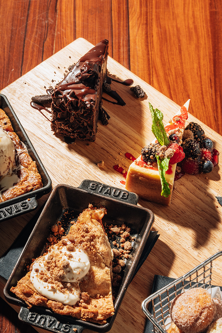 An STK Niagara Falls dessert board with chocolate cake, seasonal cheesecake with berries, an apple crumble in a Staub baker, and cinnamon-sugar donuts