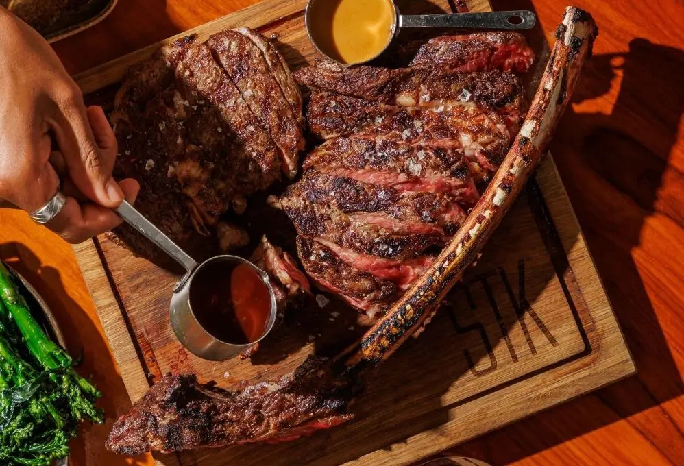 A 40oz Tomahawk steak sliced on a wooden board, finishing butter melting across the crust, at STK Niagara Falls